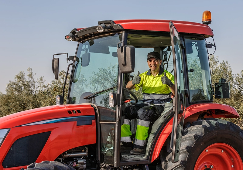 Un agricultor en su tractor con los pulgares hacia arriba.